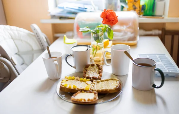 Πρωινό με τσάι και καφέ, κομμάτια φρούτων, τοστ με βούτυρο και ξηρούς καρπούς στο τραπέζι της κουζίνας το πρωί — Φωτογραφία Αρχείου