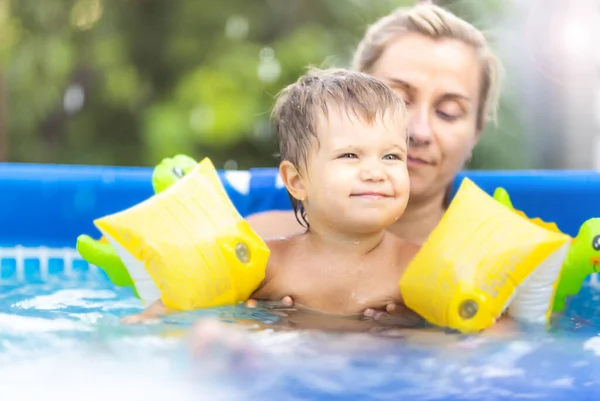 Annem havuzda kolsuz çıplak bir bebekle oynuyor yaz günbatımının arka planında. — Stok fotoğraf