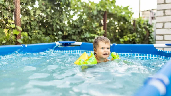 Kind in Ärmeln schwimmt im Pool im Hof — Stockfoto