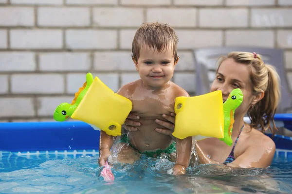 Mamá juega con un bebé desnudo en exceso en la piscina sobre el fondo de un atardecer de verano — Foto de Stock