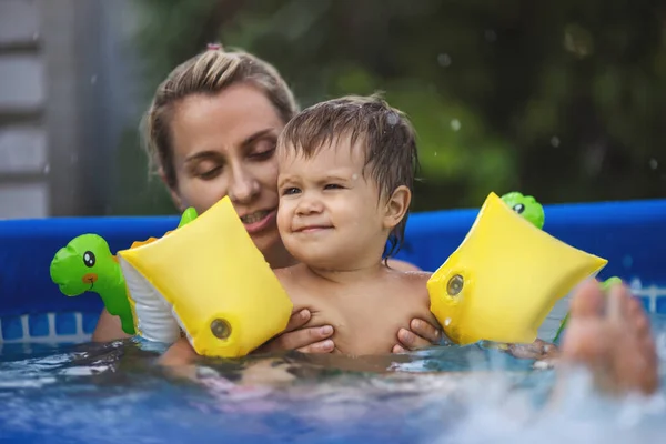 Annem havuzda kolsuz çıplak bir bebekle oynuyor yaz günbatımının arka planında. — Stok fotoğraf