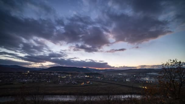 Kleine Stadt knipst bei Sonnenuntergang Lichter unter dunklem Abendhimmel an — Stockvideo