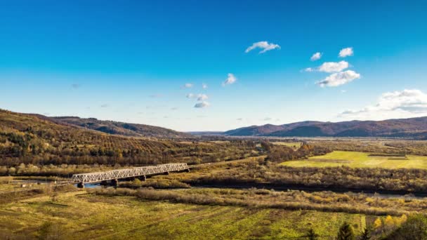 Puente del ferrocarril sobre el río en las tierras altas con árboles de colores — Vídeo de stock