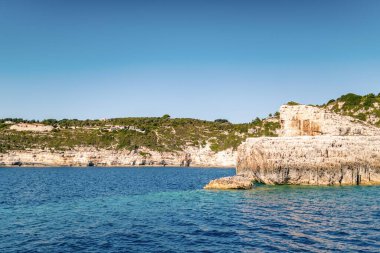 High stoned cliff on sea beach of Corfu island at sunset