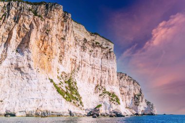 Layered rocky cliffs with plants near shore of Corfu island