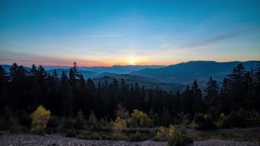Gün batımından gün batımına kadar tepeler boyunca dağlık arazide kozalaklı ormanlar.