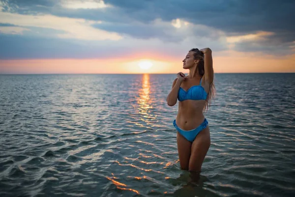 Girl with blond hair in a swimsuit posing against the backdrop of the sunset in the estuary enjoying nature around him — Stock Photo, Image