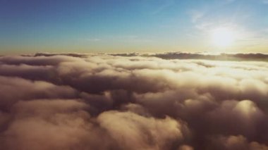 Güneş, gün doğumunda beyaz kabarık bulutların üzerinde parlıyor.