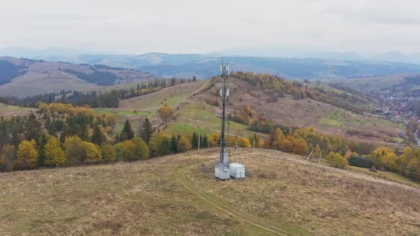 Cell tower near mountain settlement under gloomy sky — Vídeos de Stock