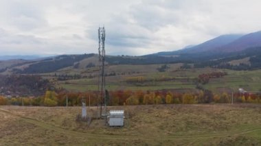 Cell tower near mountain settlement under gloomy sky