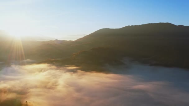 Zonsopgang licht tussen wolken boven bergachtige canyon in mist — Stockvideo