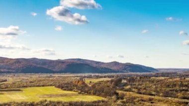 Dağlık arazide renkli ağaçlarla dolu bir nehir üzerindeki demiryolu köprüsü.
