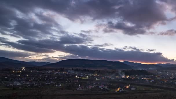 Malé město rozsvítí světla pod tmavou večerní oblohou při západu slunce — Stock video
