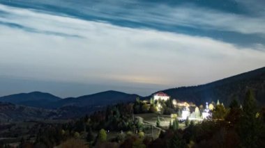 Yıldızlı gökyüzü, şehrin üzerinde süzülen beyaz bulutlarla dağlık bölgede