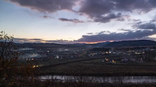 Kleine stad doet licht aan onder donkere avondhemel bij zonsondergang — Stockvideo