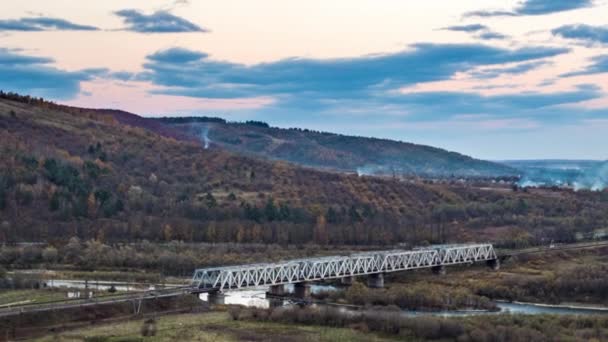 Railroad bridge over river in highland valley at sunset — Vídeo de Stock