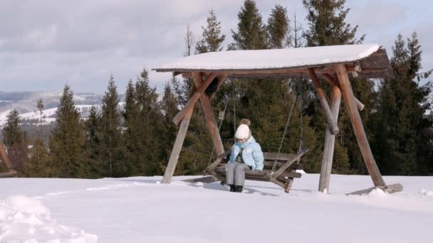 Mała dziewczynka korzystających huśtawki w górach zimowych. — Wideo stockowe