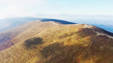 Mavi bulutlu gökyüzünün altındaki dağ sırtında dar yollar