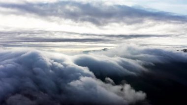 Pembe gün batımında dağ tepelerini kaplayan yoğun sis.