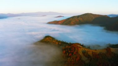 Dağ tepeleri renkli ormanlar ve yoğun sis ile kaplı.