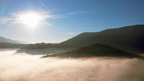 Luz do nascer do sol entre as nuvens acima do cânion montanhoso em névoa — Vídeo de Stock