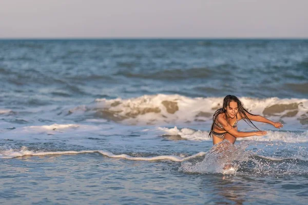 머리가 늘어져 있는 한 소녀는 파도를 타고 바다를 거닐며 햇빛을 즐긴다 — 스톡 사진