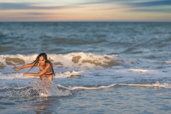 Una chica con el pelo suelto camina sobre el mar con olas y disfruta del sol —  Fotos de Stock