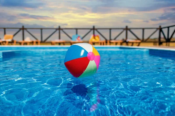 La pelota flota en la superficie del agua en la piscina bajo el sol de verano — Foto de Stock
