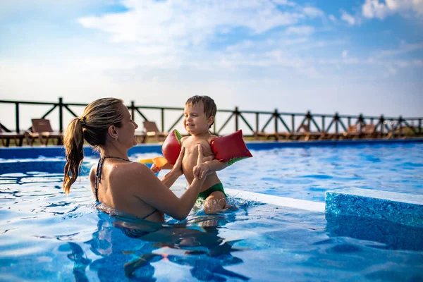 Mamá juega con su hijo con las sobras en la piscina en verano —  Fotos de Stock
