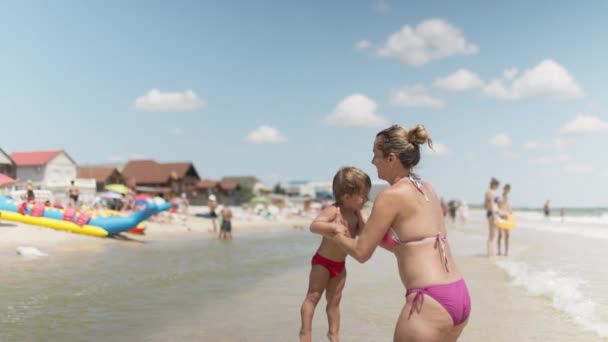 Мама выбрасывает сына за море на летние каникулы под теплым солнцем — стоковое видео