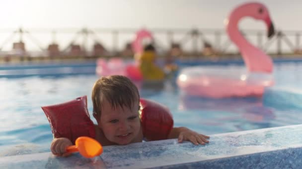 Хлопчик з пов'язками і незадоволеним обличчям, намагаючись вийти з басейну чистої води і закликаючи свою матір — стокове відео