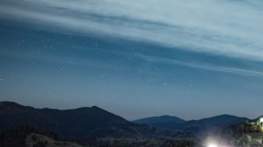 Yıldızlı gökyüzü, şehrin üzerinde süzülen beyaz bulutlarla dağlık bölgede