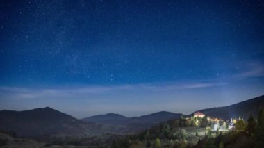 Yıldızlı gökyüzü, şehrin üzerinde süzülen beyaz bulutlarla dağlık bölgede