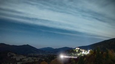 Yıldızlı gökyüzü, şehrin üzerinde süzülen beyaz bulutlarla dağlık bölgede