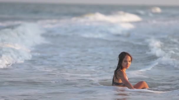 Flicka med vått hår i en leopard baddräkt stänk vatten medan du sitter i havet — Stockvideo