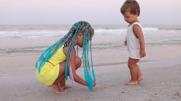 Starší sestra hraje s mladším bratrem na mělčině u pobřeží na letní dovolenou — Stock video