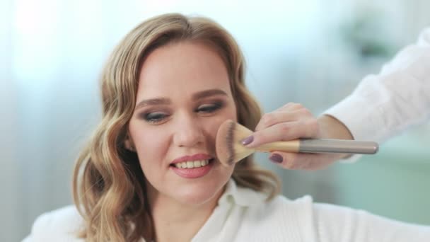 Mujer bonita aplicando maquillaje en el salón de belleza. — Vídeo de stock