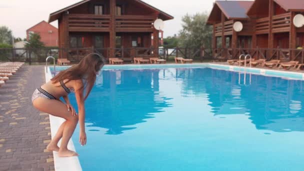 Ragazza in costume da bagno leopardo prova l'acqua in piscina — Video Stock