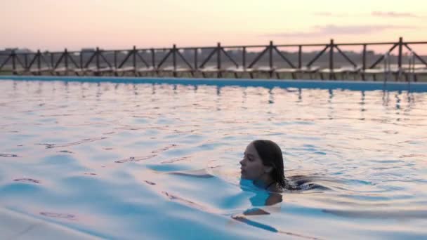 Девушка в купальнике играет в бассейне под летним солнцем — стоковое видео