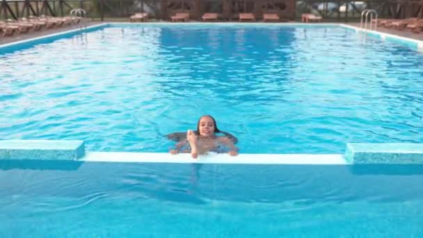 Chica en traje de baño de leopardo jugando en la piscina bajo el sol de verano — Vídeo de stock