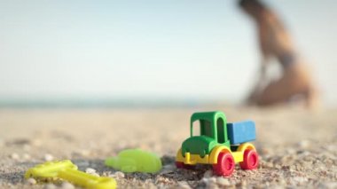 Birçok oyuncak, yaz güneşinin altında, deniz kıyısındaki sahilde yatıyor.