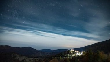 Yıldızlı gökyüzü, şehrin üzerinde süzülen beyaz bulutlarla dağlık bölgede