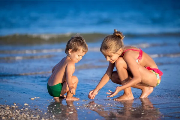 Older sister playing with younger brother aground near the shore on summer vacation — Stock Photo, Image