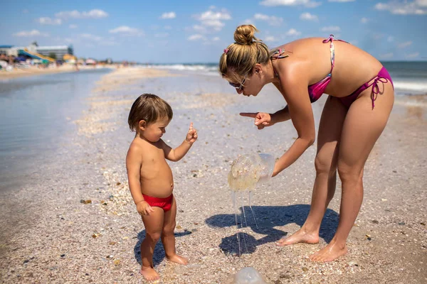 Mamá muestra a su hijo una medusa de pie en la costa del mar — Foto de Stock