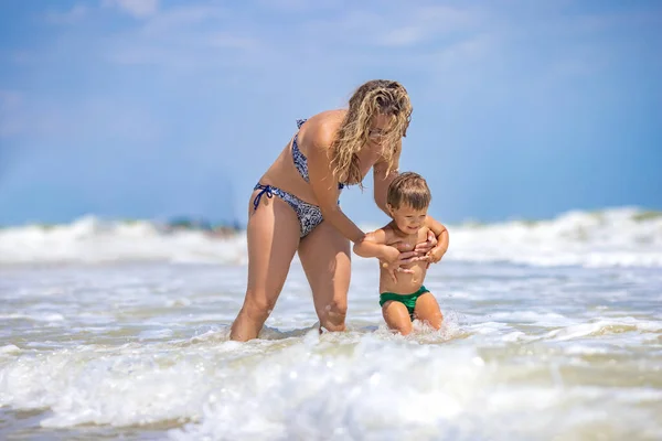Mom throws her son up over the sea on summer vacation under the warm sun — Stock Photo, Image
