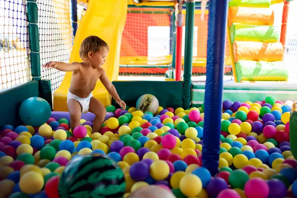 Дитина грає в ігровій кімнаті і котиться по слайду в басейн з маленькими кульками — стокове фото