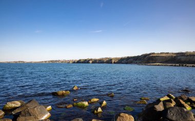 Sakin Bulgar deniz manzarası, sakin mavi yansıtıcı Karadeniz ve parlak güneşli akşam günbatımına karşı eski kayalık taşlar.