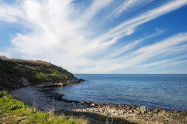 Sakin Bulgar deniz manzarası, sakin mavi yansıtıcı Karadeniz ve parlak güneşli akşam günbatımına karşı eski kayalık taşlar.