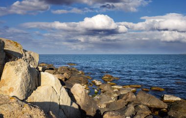 Sakin Bulgar deniz manzarası, sakin mavi yansıtıcı Karadeniz ve parlak güneşli akşam günbatımına karşı eski kayalık taşlar.