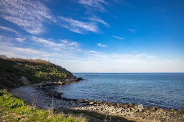 Sakin Bulgar deniz manzarası, sakin mavi yansıtıcı Karadeniz ve parlak güneşli akşam günbatımına karşı eski kayalık taşlar.